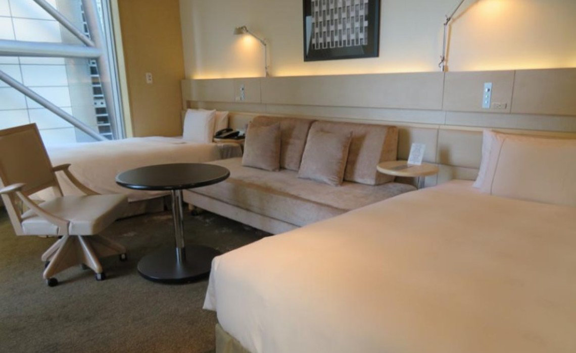 Modern accessible room at Royal Park Hotel Tokyo Shiodome with two beds, sofa, desk chair, and wide layout. Roll-in shower included.