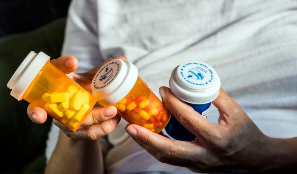 Banned and Restricted Medications in Japan — bottles of medication held by someone in their hands.